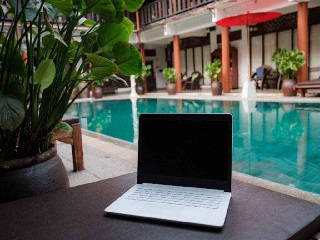 Laptop kept by pool on a table